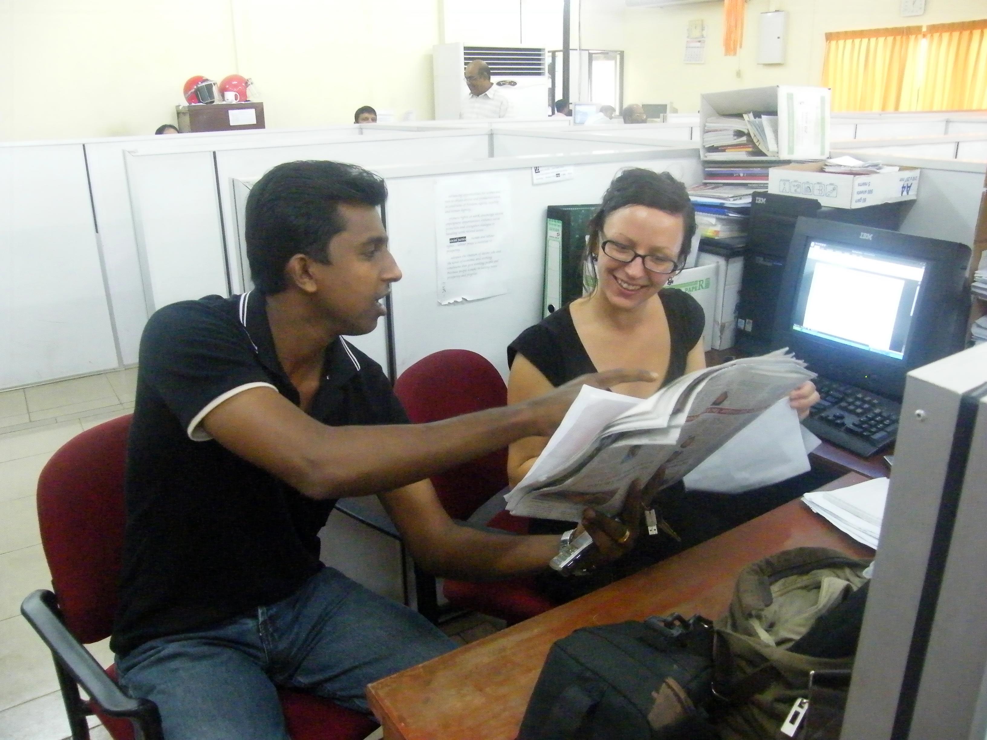 A business intern in Sri Lanka and local staff read through newspapers at their placement. A Projects Abroad intern at her business placement in Sri Lanka checks the day's newspaper with local staff.